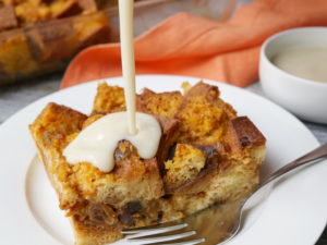 pouring vanilla sauce on pumpkin bread pudding